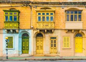 malta, valletta - fachada de una casa residencial con balcones tradicionales malteses. casa de ladrillos amarillos en la calle de malta. foto
