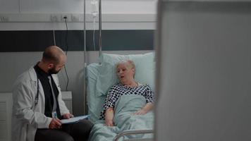médico y enfermera haciendo consulta con paciente jubilado video