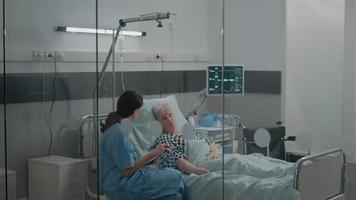 assistente médico fazendo consulta de verificação para o paciente na cama da enfermaria do hospital video