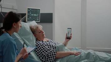 Aged patient holding smartphone for video call with doctor