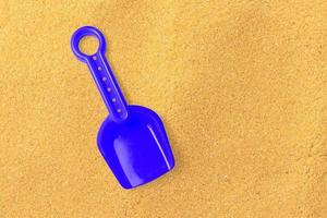 Close up view blue sand shovel isolated on sand beach. added copy space for text. photo