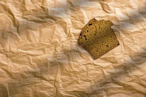 pan de centeno en rodajas sobre un fondo marrón aislado. rebanadas de pan integral envueltas en papel marrón. foto