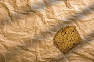 pan de centeno en rodajas sobre un fondo marrón aislado. rebanadas de pan integral envueltas en papel marrón. foto