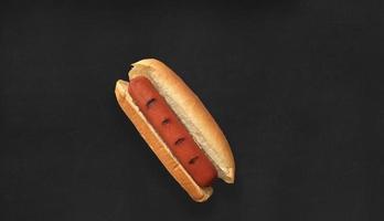 vista de cerca delicioso hot dog. aislado sobre fondo negro. adecuado para su proyecto de diseño de alimentos. foto