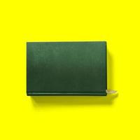 concepto de regreso a la escuela, tapa dura, cierre frontal de libro verde oscuro aislado en amarillo. foto