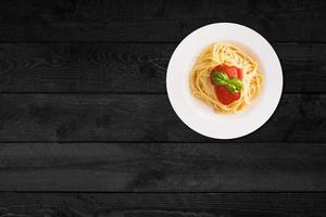 Close up view of spaghetti with ketchup isolated on black wooden table. photo