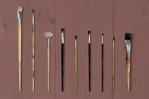 Set of different brushes isolated on wooden background. photo