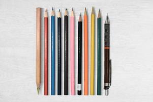 Set of colored pencils isolated on bright wooden background.