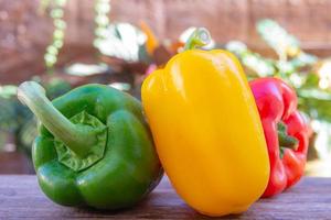 Yellow sweet pepper, red and green on the old wooden table. photo