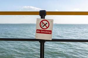 Señal de advertencia de no fumar frente al mar azul. foto