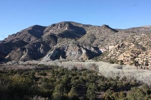 Vista de árboles ribereños sin hojas y vastas montañas desde la carretera a Turkey Creek foto