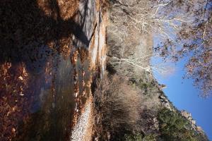 El arroyo de aguas bravas brilla mientras se escurre desde la pasarela en un día fresco con hojas de otoño foto