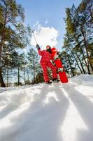 Mujer con la tabla de snowboard con smartphone en un palo para hacer selfie foto