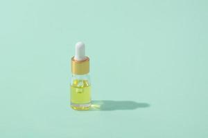 Dropper bottle with cosmetic oil or serum with pipette on mint background photo