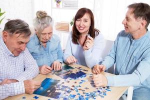 Senior couple and middle age couple solving jigsaw puzzle together with family at home photo
