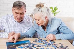 Senior couple solving jigsaw puzzle together at home photo