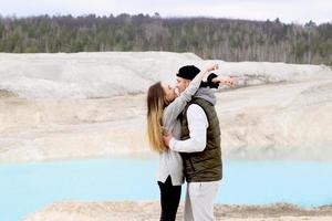 Happy couple hugging and looking at each other on the background of blue lake and sandy mountain photo