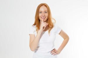 Portrait of happy red hair woman showing silence gesture and looking at camera isolated over white background photo