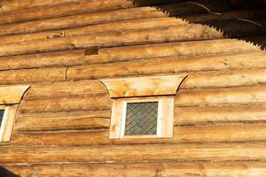 una vieja ventana con plataformas en el fondo de una pared de troncos. foto