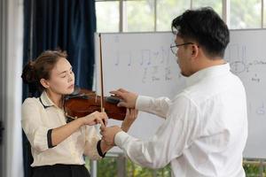 Student Learning How to Play Violin With Teacher in Classroom photo