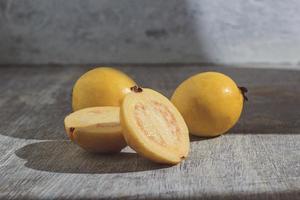 Guayaba amarilla sobre fondo de madera. vitamina c, dieta de frutas saludables. foto