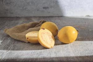Guayaba amarilla sobre fondo de madera. vitamina c, dieta de frutas saludables. foto