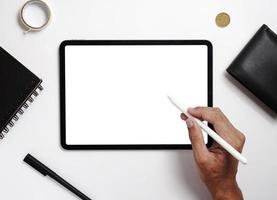 Men use digital tablets on desks with blank screens for mock up. A flat lay image of a man holding a stylus pen with a blank copy space screen for your text message or information content. photo