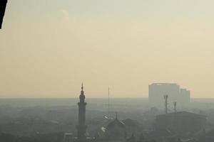 la mezquita en medio de la ciudad está envuelta en una espesa niebla. magnífica mezquita fotografiada desde drone foto