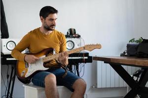 young boy with beard playing guitar at home