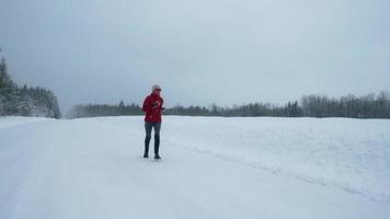 kvinna joggar på snöig avlägsna väg