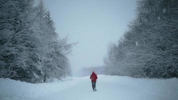 View of woman running on empty snowy road video