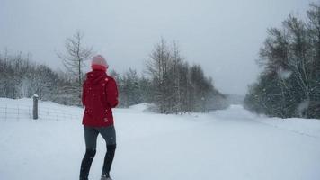 vista de mulher correndo em uma estrada vazia de neve video