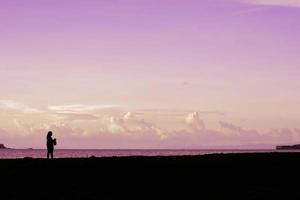 una niña sola en la playa al anochecer. una chica disfruta de mi tiempo. foto