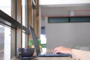 Man using laptop online, seated at office table, staring at computer screen, focused male using internet banking, sending email, and searching for information photo