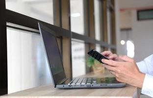 Primer plano de las manos de un hombre tomadas con un teléfono inteligente, en el café, un hombre está en su teléfono, escribiendo mensajes en las redes sociales. foto