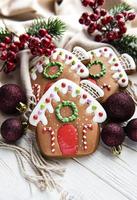 Homemade gingerbread houses  fir-tree branches and berries on white wooden table. photo