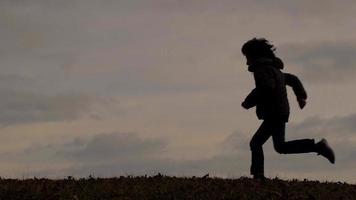 Kind in Silhouette beim Laufen auf einer Wiese video