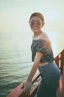 Retrato de hermosa mujer de pie contra la luz del atardecer en el muelle de la playa foto