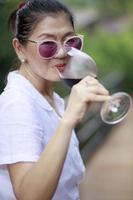 Mujer asiática bebiendo vino tinto en vidrio de lujo foto
