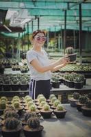 Mujer relajante en suculento jardín sosteniendo melocactus pot en la mano foto