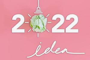 año nuevo 2022 idea creativa y concepto de inspiración, poder de las ideas de imaginación con bombilla de papel para el plan de estrategia de creatividad en el año 2022. diseño de banner de idea de pensamiento de visión sobre fondo rosa foto