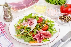 Fresh homemade salad with arugula, jamon, rucola, tomatoes, parmesan. photo