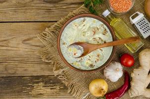 Sopa de verduras con lentejas en cuenco de barro en la mesa foto