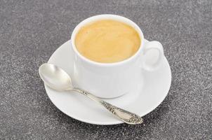 White cup espresso with foam on gray stone background. photo