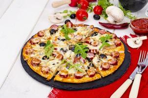 Tasty pizza with salami, mozzarella, mushrooms and olives on wooden background. photo