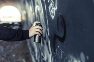 Cerrar la mano de la persona rociar pintura con aerosol graffiti wall foto