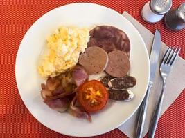 Set of dishes on breakfast table. Scrambled eggs, omelette, pate, croissants, champignons, crispy bacon, sausages. photo