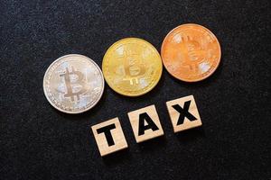 Cryptocurrencies with TAX word on dark wood background photo