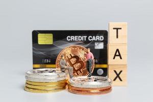 Miniature people, Businessman with Crypto Currency and wooden letters TAX photo