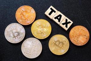 Cryptocurrencies with TAX word on dark wood background photo